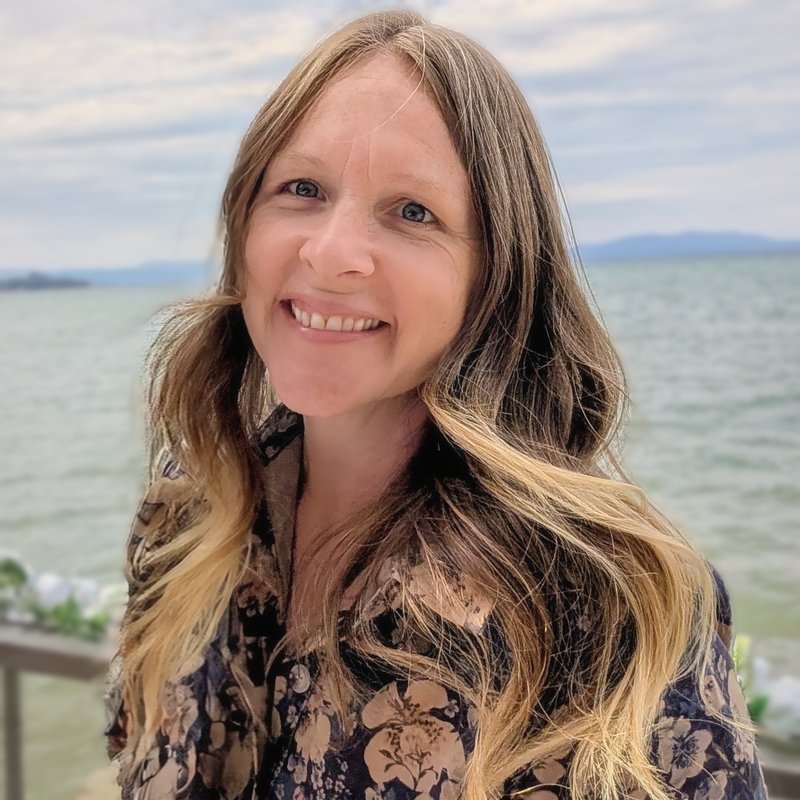 Carah Gilmore smiling outdoors by a lake